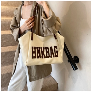 Detail view of large cream tote bag with brown straps and HNKBAG letter print