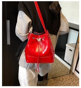 Close-up of a red PU leather bucket bag featuring a decorative metal butterfly charm