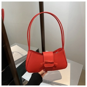 Detail of red bow baguette bag featuring smooth PU leather texture and shoulder straps