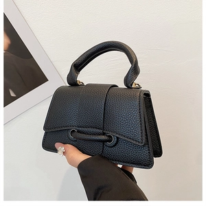 Detailed close-up of black lychee grain leather mini bag with gold hardware and top handle
