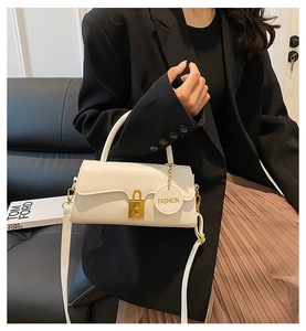 Detailed view of white leather crossbody bag with golden lock and Fashion charm pendant