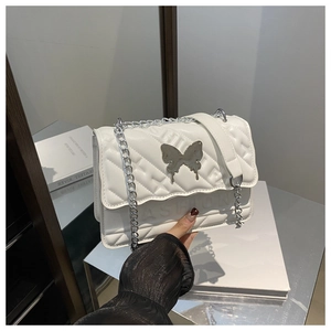 Gros plan d'un sac matelassé blanc avec boucle papillon argentée et bandoulière