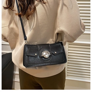 Détail d'un sac à bandoulière noir avec boucle en métal en forme de planète