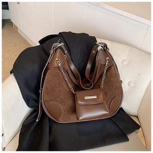 Detail of dark brown bucket bag featuring contrast suede patchwork and metal chain