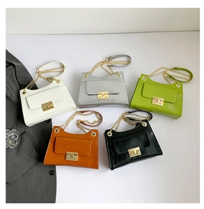 Flat lay of five colorful crossbody square bags with gold chains and lock details