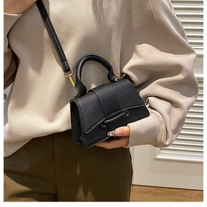 Detail shot of black pebble leather texture and iconic curved base of the small handbag