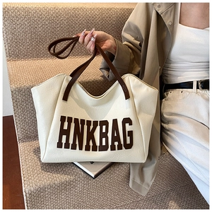 Detailed view of large cream leather tote bag with brown straps and HNKBAG letter print