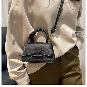 Detail of black litchi texture handbag with U-shaped buckle and adjustable shoulder strap