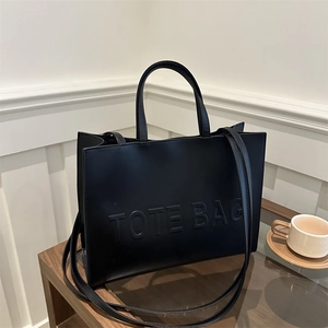 Minimalist black leather tote bag with embossed lettering and dual shoulder straps