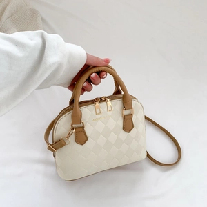 Minimalist beige shell crossbody bag with quilted pattern and brown leather top handle