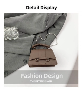 Détail du mini sac en cuir grainé marron avec chaîne sur un blazer gris élégant