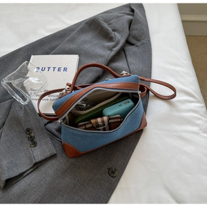 Detail view of denim and leather crossbody bag showing interior storage capacity