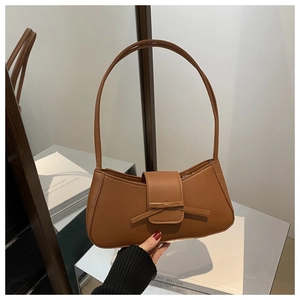 Close-up of a brown baguette bag with a decorative bow and smooth leather texture