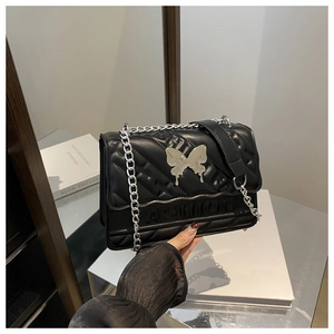 Détail du sac à bandoulière matelassé noir avec fermoir papillon argenté et chaîne