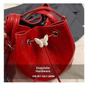 Macro detail of red textured leather bucket bag with silver butterfly metal hardware