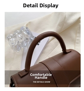 Detail view of brown matte leather handbag handle with reinforced stitching and soft texture