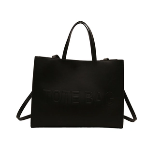Minimalist black matte leather tote bag with embossed lettering and adjustable strap