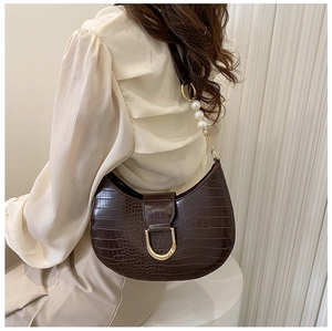 Detail of dark brown crocodile-embossed hobo bag featuring luxury pearls and golden buckle