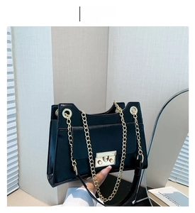 Detail of black rectangular crossbody bag with gold chain strap and metallic lock