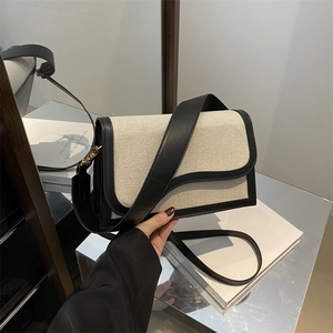 Minimalist canvas shoulder bag with black leather trim and gold metal buckle detail