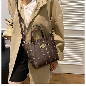 Détail d'un sac cabas marron texturé avec motifs d'ours dorés et anses en cuir