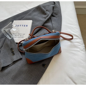 Detailed interior of denim handbag with brown leather trim and silver metal hardware