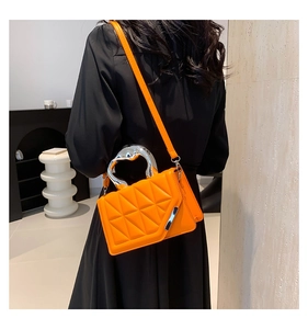 Quilted orange handbag with metallic top handle and crossbody strap on a model