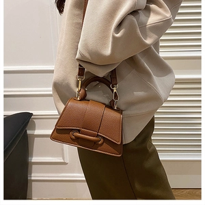 Brown lychee leather crossbody bag with curved base shown as a stylish handheld accessory