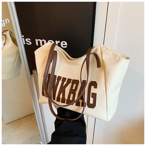 Detail of off-white tote bag showing NKBAG letter print and brown leather handles