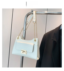 Detail of white leather shoulder bag featuring gold chain strap and metal buckle closure