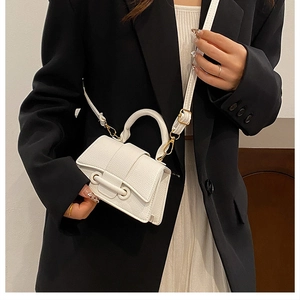 Detailed view of white litchi pattern mini handbag with gold hardware on a model