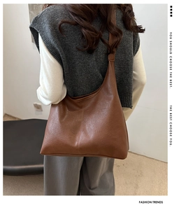 Rear view of model wearing a vintage brown lychee grain leather hobo tote with wide strap