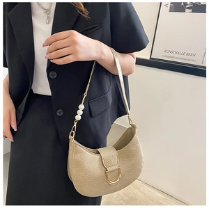Detail of beige faux crocodile texture bag with gold horseshoe buckle and pearl strap