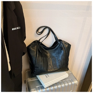 Detail of black large tote bag with HNK BAG embossing on a silver suitcase