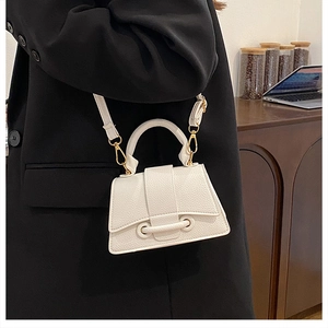 Close-up of cream textured leather hourglass handbag with gold hardware on a model