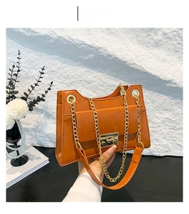 Close-up of brown faux leather square bag with gold metal chain and turn-lock closure