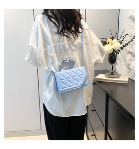 Detail of light blue quilted handbag with chunky silver metal handle and sleek texture