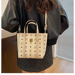 Sac seau beige à motifs d'ours porté par un mannequin en veste de cuir tendance