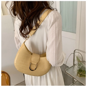 Creamy yellow half-moon bag with crocodile texture and gold D-ring worn by a model