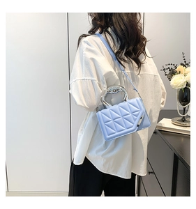 Close-up of light blue quilted leather bag featuring a unique silver metallic handle