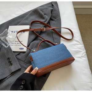 Detail of the blue denim and brown leather patchwork handbag on a soft background