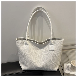 Detail shot of the white woven leather texture and dual straps on the large tote bag