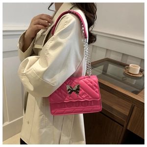 Détail du sac bandoulière rose avec motif gaufré et boucle papillon argentée élégante