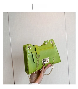 Detailed shot of vibrant green textured leather bag with gold chain and clasp closure