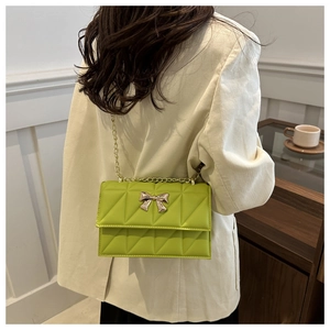 Borsa a tracolla trapuntata verde lime con fiocco dorato indossata sulla spalla