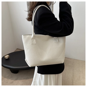 Close-up of white woven leather tote bag texture and side profile on a fashion model