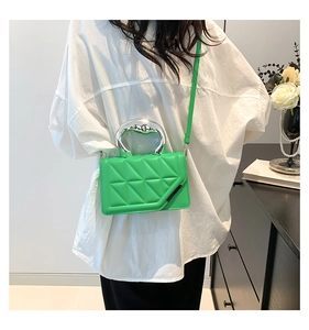 Close-up of bright green quilted mini bag featuring a unique silver metallic handle