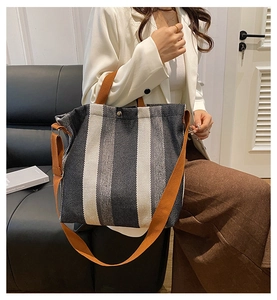 Vertical striped canvas tote bag detail showing thick weave texture and brown shoulder strap