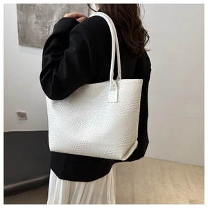 Detail of white woven tote bag with intricate checkerboard pattern on casual wear