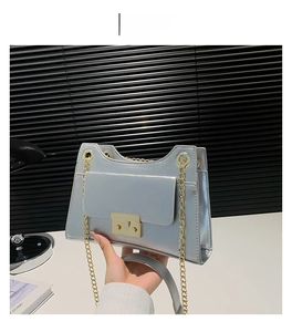 Detail of silver chain bag with gold metal lock and glossy metallic texture finish